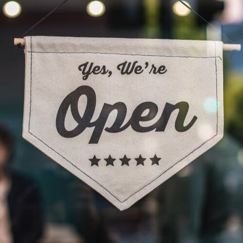 A sign that says "Yes, We're Open" lotus flowers in a pond